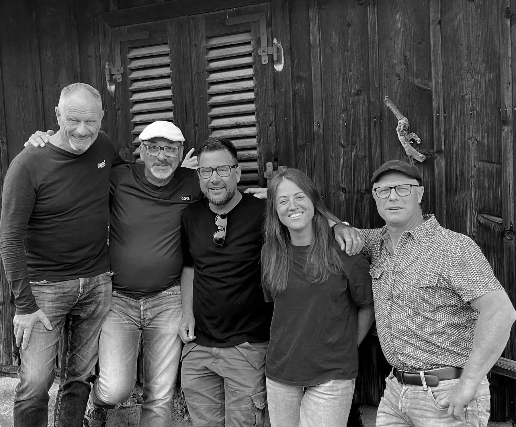 Die fünf Bandmitglieder von JIST arm in arm vor einer dunklen Holzwand des Stalls